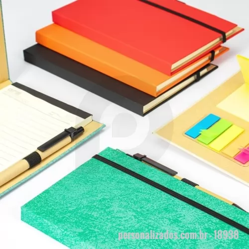 Bloco Anotações personalizado - Descrição: Bloco de anotações com capa dura revestida em papel especial e fita elástica para fechamento. Possui cerca de 80 folhas pautadas, além de um bloco com aproximadamente 20 folhas autoadesivas amarelas e por volta de 100 marcadores de página autoadesivos, divididos em cinco cores diferentes. Acompanha uma caneta esferográfica com carga azul de 1.0mm e acionamento por clique, corpo em papelão e demais componentes em plástico.  Largura :  13 cm  Espessura :  1,4 cm  Comprimento :  18 cm  Medidas aproximadas para gravação (CxL):  18 cm x 9,5 cm (capa) - 0,8 cm x 10 cm (caneta)