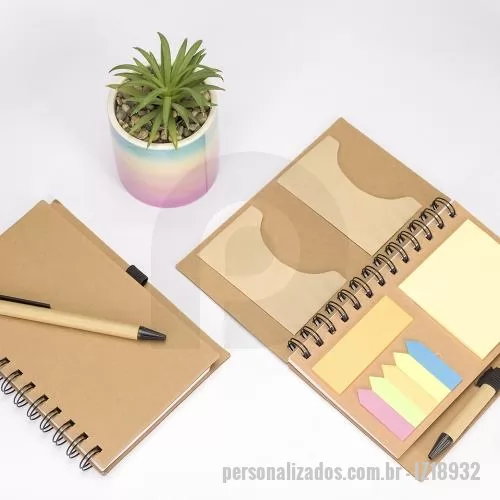 Bloco ecológico personalizado - Um caderno de capa dura em papelão com porta-canetas elástico, encadernação Wire-O e dois bolsos interiores. Contém aproximadamente 70 folhas brancas com pauta além de um bloco com cerca de 20 folhas amarelas autoadesivas. Inclui também seis blocos d