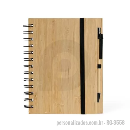 Bloco personalizado - Caderno ecológica com caneta. Capa de papelão com folha similar ao bambu. Possui aproximadamente 70 folhas brancas pautadas com logo reciclado na lateral inferior. Acompanha suporte elástico de nylon com uma caneta de papelão de detalhes plásticos.