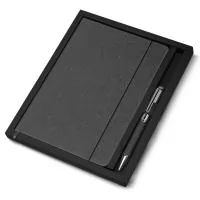 Kit caderno de anotações e caneta. O kit acompanha a caneta, e sua embalagem é presentável. O caderno de anotações é feito de material reciclável, em capa dura com miolo 80 folhas pautadas na cor bege.