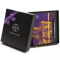 Kit composto por Bloco de capa dura revestido com couchê 150 g 4x0 cor com laminação fosca frente. Guardas em color plus 180 g 0x0 cor. Miolo sem pauta com 80 folhas em papel polém 70 g 0x0 cor, costurado, cantos arredondados, fechamento com elástico e marcador de cetim. Kit acondicionado em caixa de papel kraft preto 300 g 21 x 23 x 4 cm. A personalização é a 1 cor na tampa da caixa e à laser na caneta metálica. Laço de cetim não incluso, é opcional.
