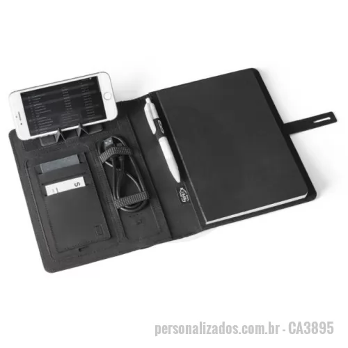 Caderno com Powerbank personalizado - Pasta A5 em 300D rPET com carregador wireless embutido. A bateria tem capacidade para 5.000 mAh, potência de 10W, entrada/saída 5V/2.1A e cabo USB tipo C para carregar a bateria. A pasta contém no seu interior um bolso para smartphone até 6.5'', três espaços para cartões, quatro luzes LED, botão on/off, suportes para esferográfica (não inclusa), celular e cabo USB, um bloco de notas com capa em cartão preto e 64 folhas pautadas de cor marfim, em papel proveniente de gestão florestal sustentável. Na frente existe ainda uma impressão oval em preto para indicar a área de carga do wireless. Fornecido em caixa presente. 165 x 225 x 25 mm