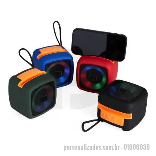 Caixa de Som com Bluetooth personalizada - Caixa de som multimídia em plástico com espaço superior para encaixe do celular e base com revestimento antiderrapante. Oferece conectividade Bluetooth e entrada auxiliar P2, além de cartão TF (microSD) e USB-C, permitindo a reprodução de arquivos MP3. Acompanha cordão de nylon e cabo USB-C para carregamento.