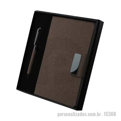 Kit executivo personalizado - Kit executivo com dois itens. O conjunto é composto por uma caderneta com capa dura em couro sintético revestido com fibra de café, no tamanho A5, com fechamento magnético, marca-páginas em fita de cetim e cerca de 80 folhas pautadas; e uma caneta metálica com detalhes do mesmo material, acionamento por rotação e carga esferográfica azul de 1,0 mm. Acompanha uma caixa de papelão com berço em espuma para a caneta.  Largura: 21 cm Profundidade: 2,4 cm Comprimento: 22 cm