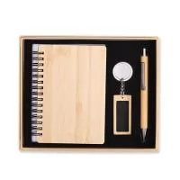 Kit executivo ecológico em bambu composto por três itens: um caderno capa dura com encadernação Wire-O e aproximadamente 68 folhas na cor marfim pautadas; caneta com detalhes em metal, topo emborrachado para uso em dispositivos touchscreen, acionamento por clique e carga esferográfica azul de 1,0 mm; e chaveiro com argola e placa personalizável em metal. Acompanha embalagem em papelão com berço em espuma para acomodação dos itens.