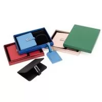 Kit de viagem composto por dois itens: porta-passaporte e tag identificadora de bagagem, ambos em poliuretano (PU). O porta-passaporte possui fechamento magnético e fivela metálica, dois bolsos internos, sendo um deles com quatro compartimentos para cartões, além de dois bolsos menores para cartões SIM. A tag identificadora apresenta aba para proteger o visor plástico e um cartão interno dupla face em papel cartão no tamanho 5,5 cm x 8,5 cm para o preenchimento de dados pessoais, além de alça lateral em PU com fivela metálica. Acompanha caixa em papelão com berço fixo em espuma de EVA com acabamento aveludado para guardar os itens do conjunto. *Diversas cores.