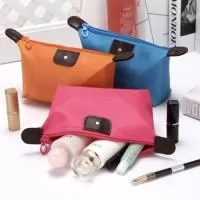 Necessaire impermeável de poliéster com detalhes em couro sintético e parte interna com revestimento emborrachado, possui um “botão” no detalhe do couro frontal.