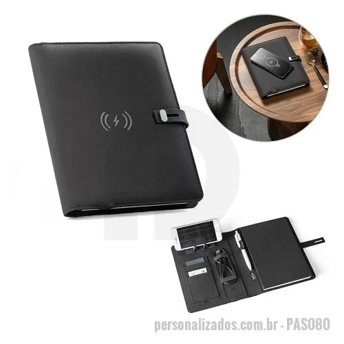 Pasta executiva personalizada - Pasta A5 em 300D poliéster reciclado (100% rPET) com carregador wireless embutido. A bateria tem capacidade para 5.000 mAh, potência de 10W, entrada/saída 5V/2.1A e cabo USB tipo C para carregar a bateria. A pasta contém no seu interior um bolso para smartphone até 6.5'', três espaços para cartões, quatro luzes LED, botão on/off, suportes para esferográfica (não inclusa), celular e cabo USB, um bloco de notas com capa em cartão preto e 64 folhas pautadas de cor marfim, em papel proveniente de gestão florestal sustentável. Na frente existe ainda uma impressão oval em preto para indicar a área de carga do wireless. Fornecido em caixa presente. Medidas: 165 x 225 x 25 mm