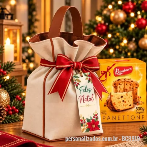 Porta panetone personalizada - Porta-panetone 500g confeccionado em lona de algodão cru, com forro interno marrom, alça reforçada em couro sintético e acabamento externo no mesmo material. Possui fechamento com laço decorativo e tag natalina personalizada.  Medidas: Comprimento: 18 cm Altura: 25 cm Largura: 18 cm  Pedido mínimo de 100 unidades  *Produto não acompanha panetone