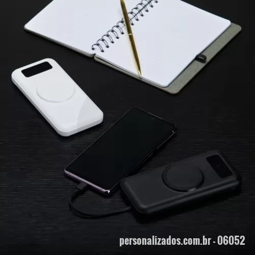 Power bank personalizado -  Carregador portátil com capacidade para até 10.000mAh. Conta com display digital que indica o percentual de bateria do próprio carregador, área para carregamento de dispositivos compatíveis com tecnologia de indução e quatro cabos com saídas micro-USB, USB-C, Lightning e USB-A. Dispõe ainda de entradas micro-USB e USB-C exclusivas para a recarga do próprio carregador.